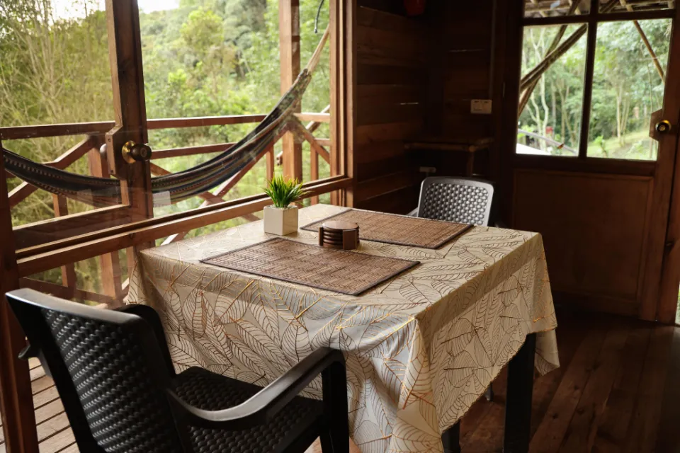 Comedor junto a la ventana, con una hamaca colgada en el balcón.
