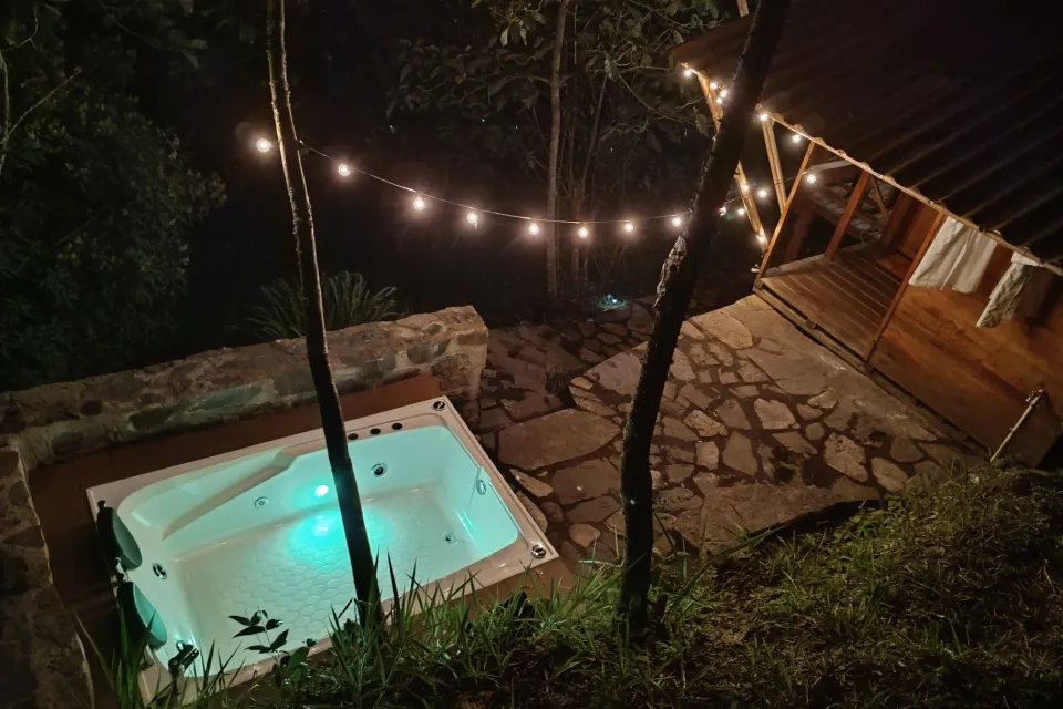 El jacuzzi de piedra de noche, bajo una línea de luces colgantes.