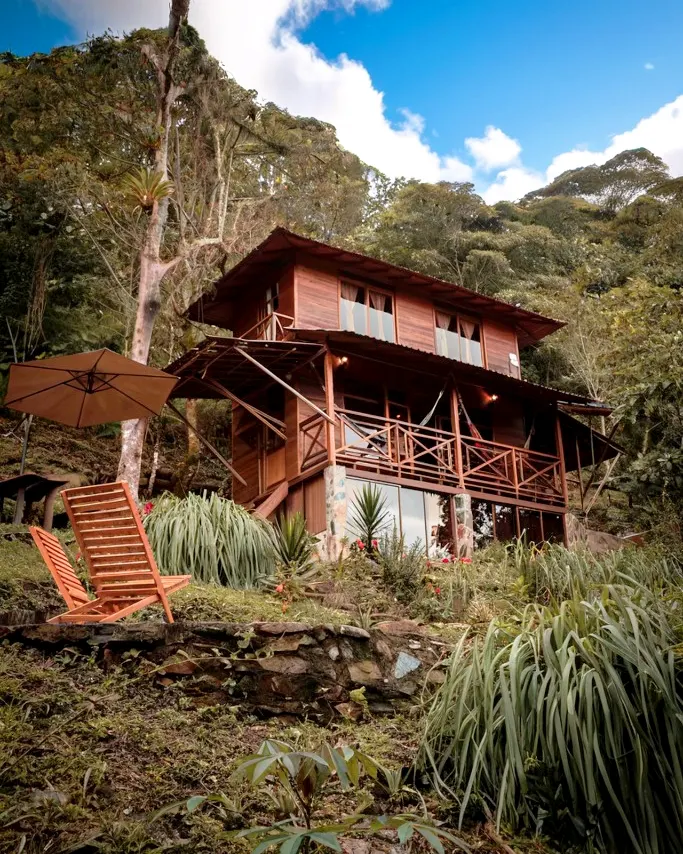 La cabaña de dos niveles vista desde el jardín, entre el bosque.