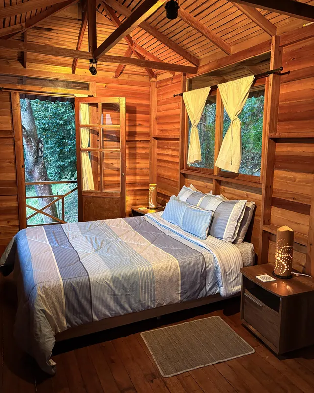 Habitación con cama doble, mesas de noche y paredes de madera.