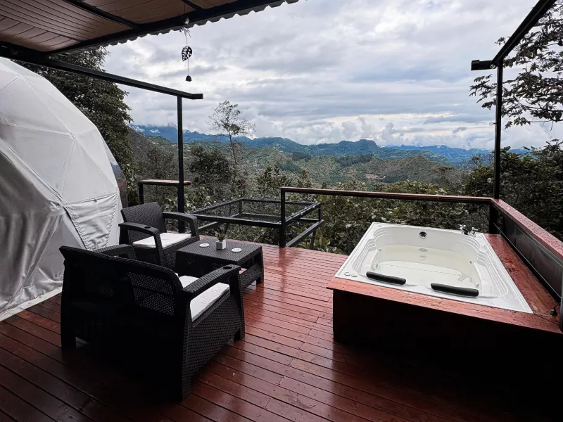 Terraza del glamping junto al domo, con jacuzzi y vista a las montañas.