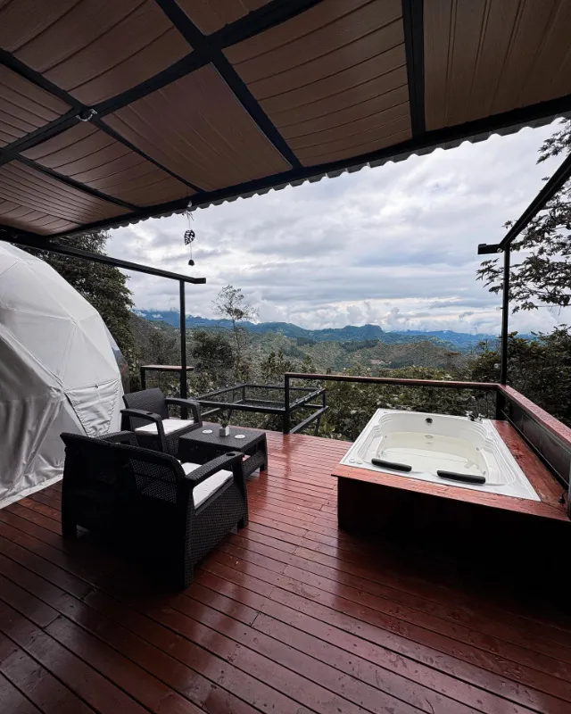 Terraza cubierta del glamping con el jacuzzi y la vista a las montañas.