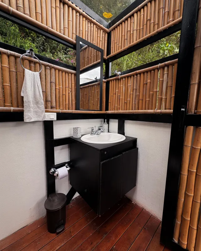 Baño con paredes de guadua y lavamanos blanco.