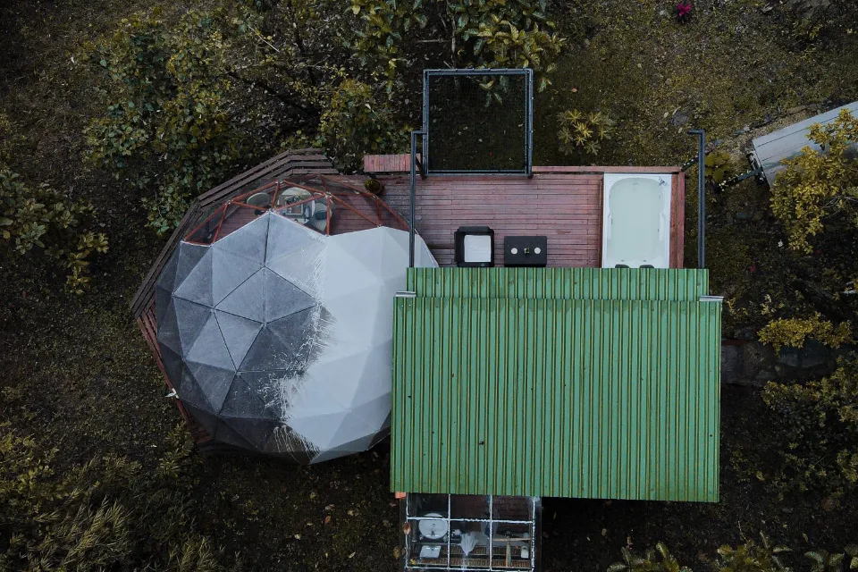 Foto aérea cenital: el domo, la terraza y el jacuzzi rodeados de bosque.